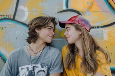 Una coppia di adolescenti si scatta foto a vicenda in un ambiente esterno panoramico, sorridendo.