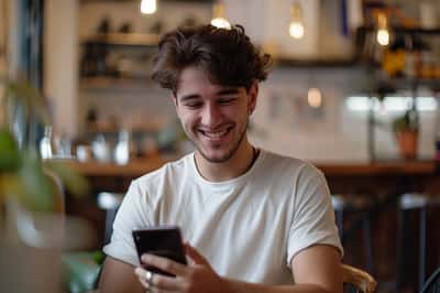 Ruka osoby držící telefon, s mnoha ikonami srdíček „lajků“ plovoucími po obrazovce.